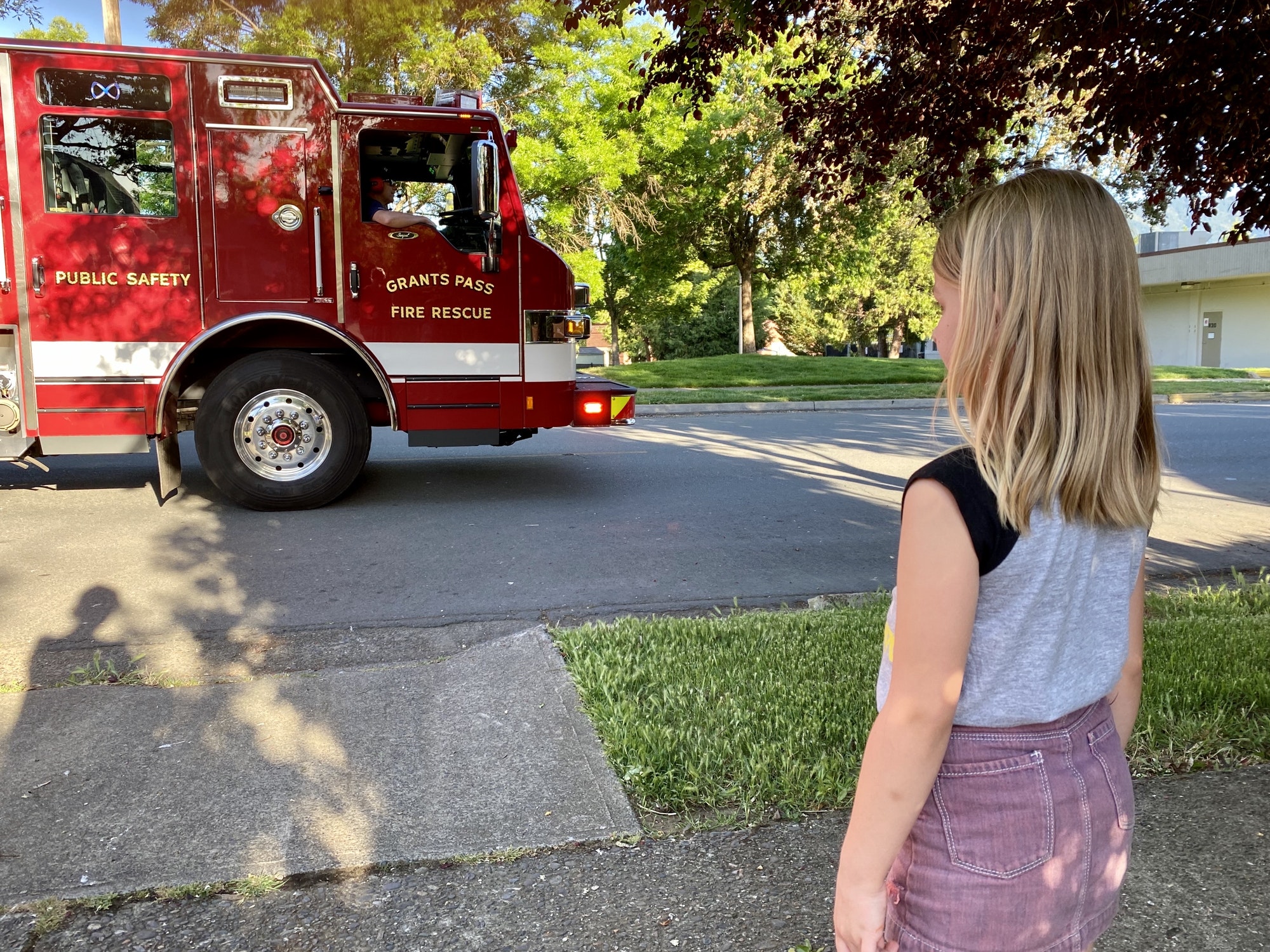 A little girl watching a fire truck.