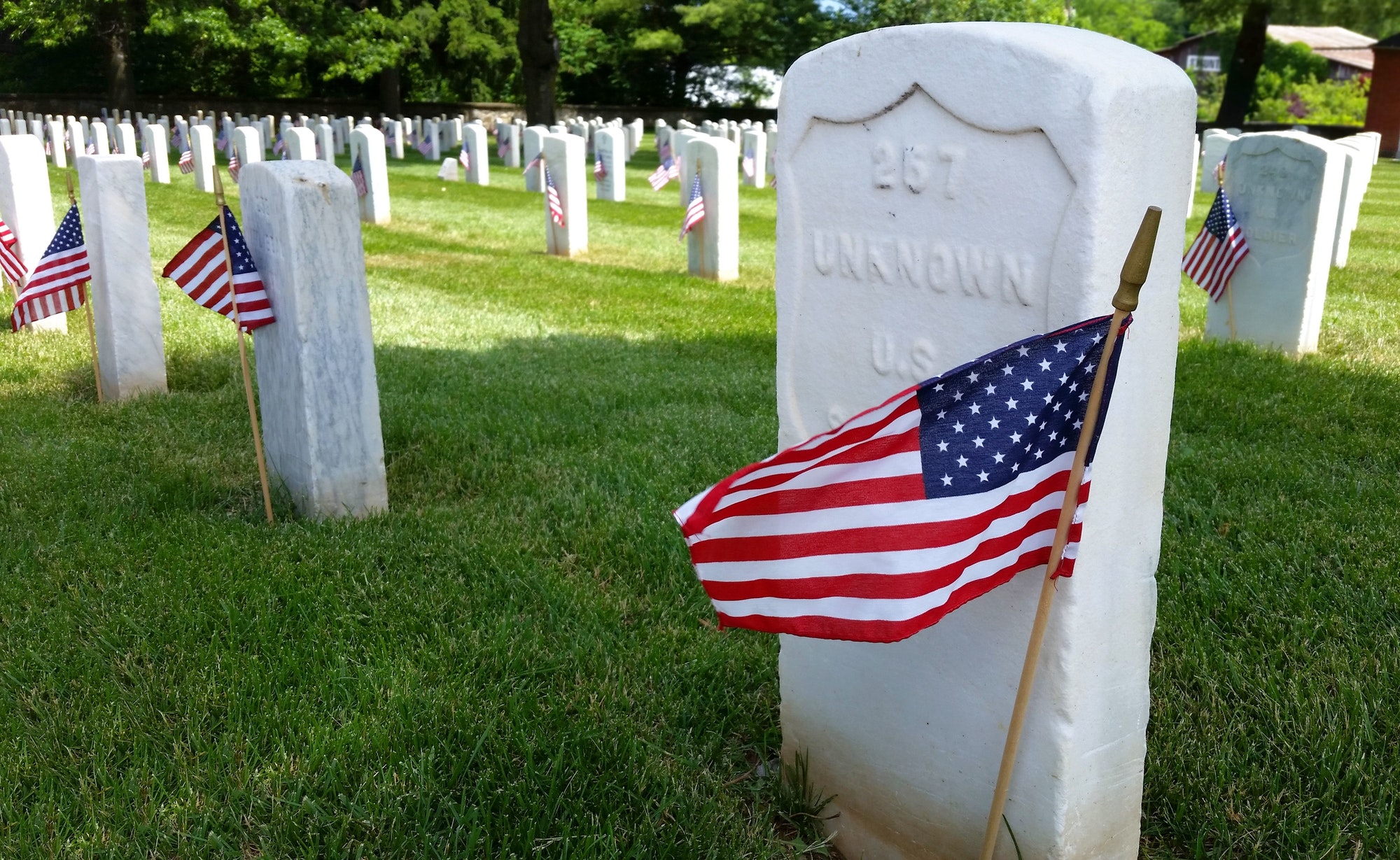 Rows of grave stones in a National cemetery decorated with American flags for Memorial Day.