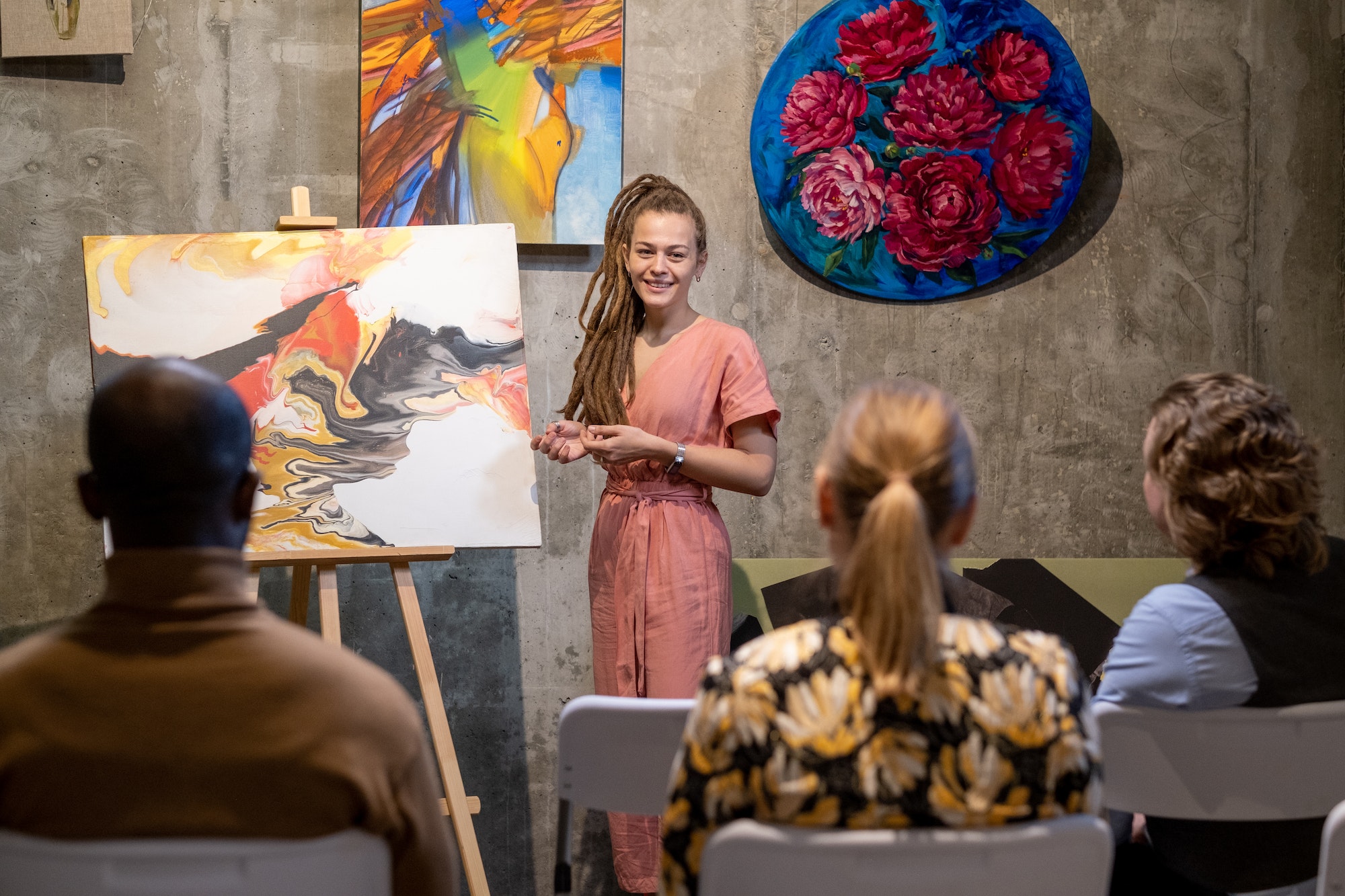 Happy young female auctioneer presenting abstract painting