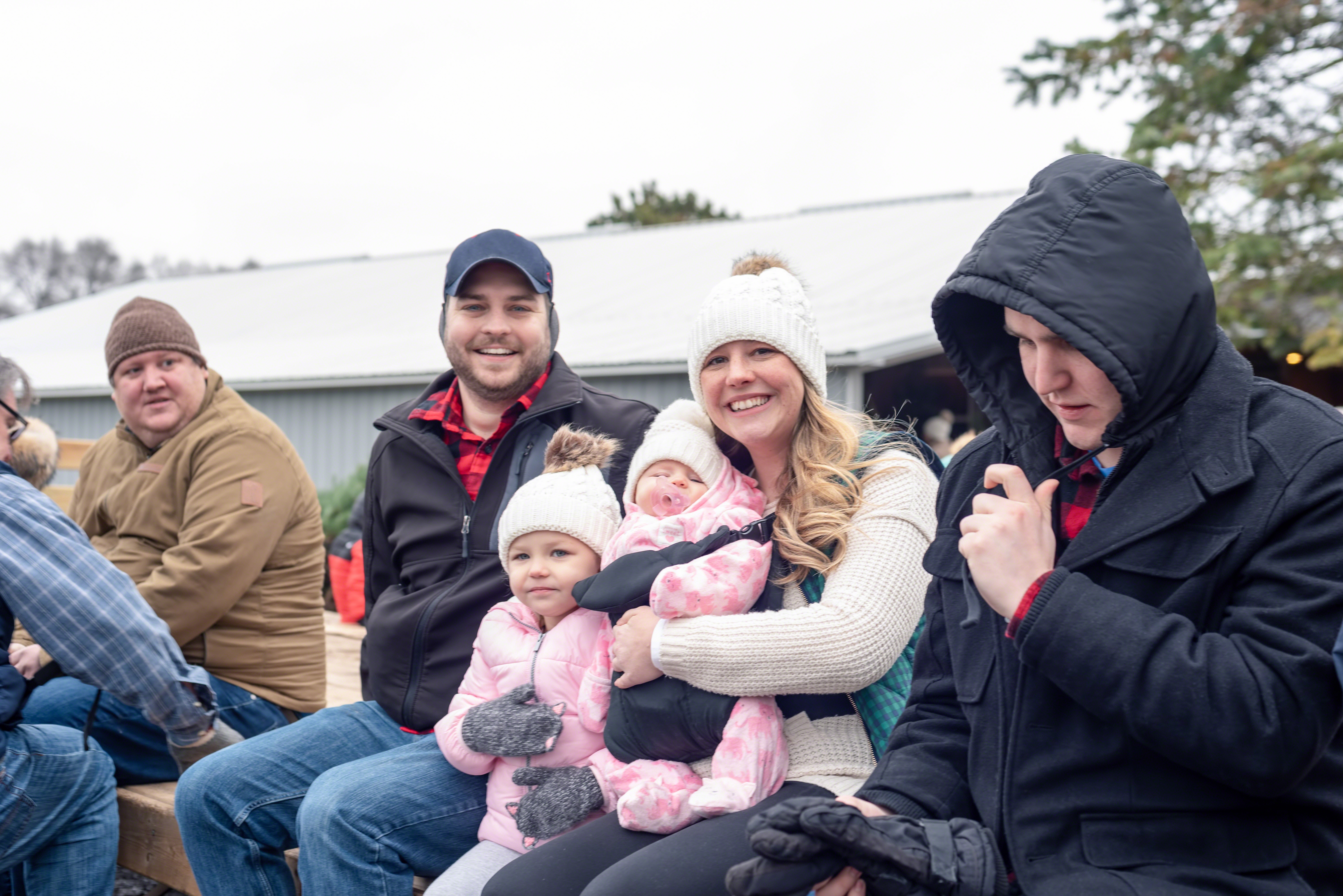 Happy family group riding a wagon out to the Christmas tree farm