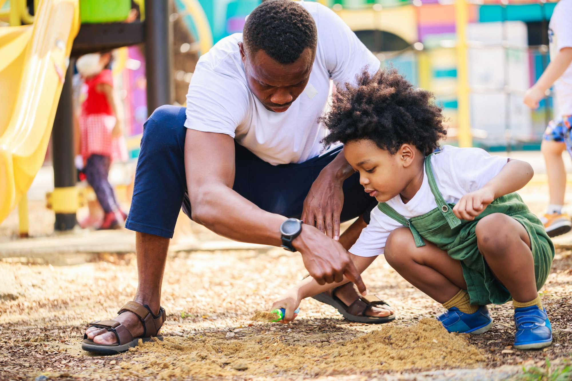 Happy African American Parents play in the playground area together in the park