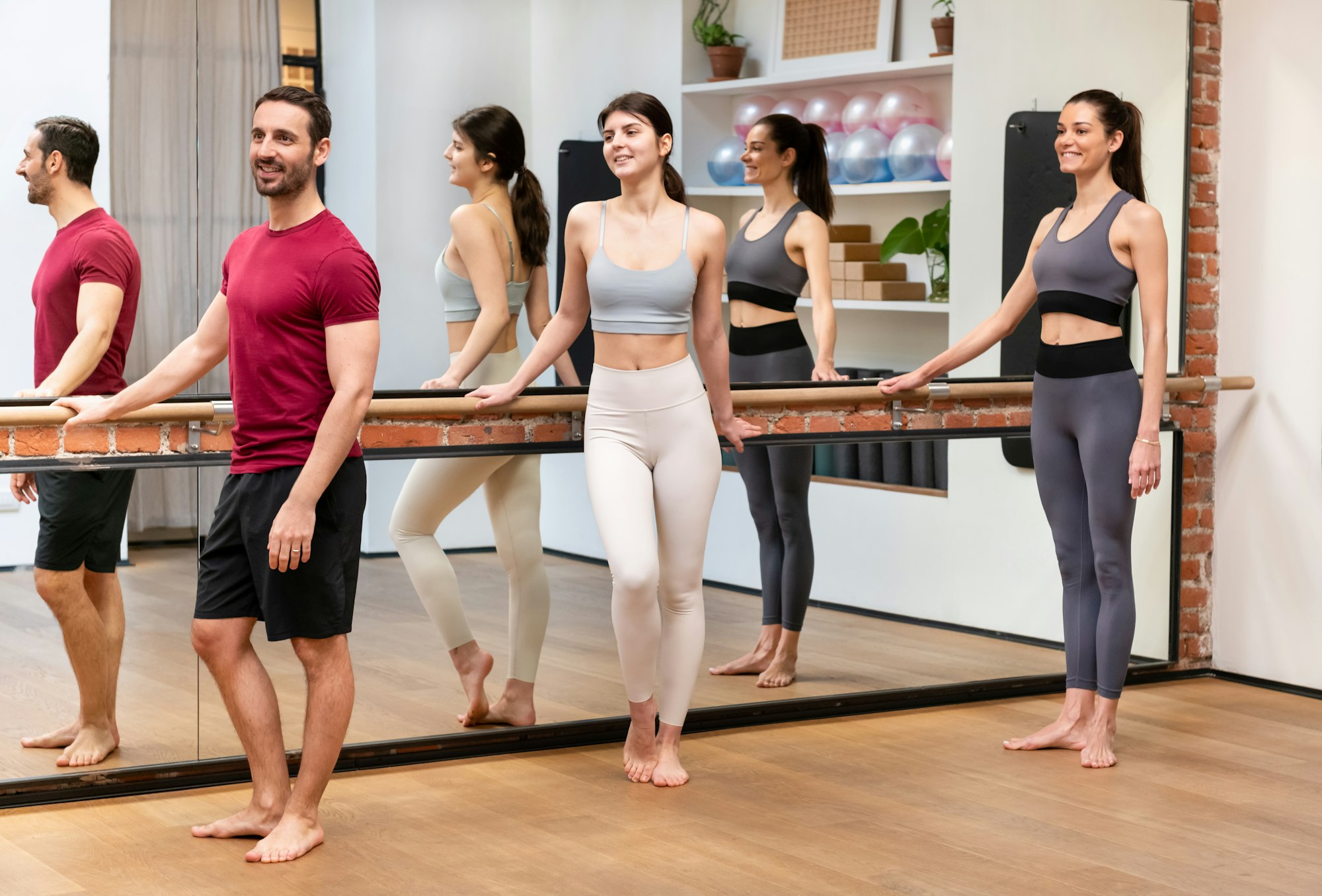 Group of athletic people standing near barre during training