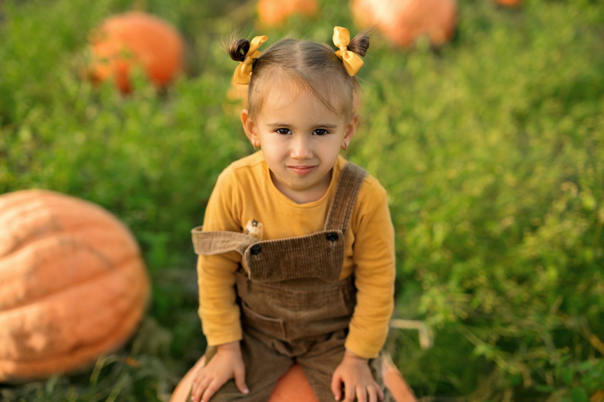 A child is sitting on a pumpkin in the garden