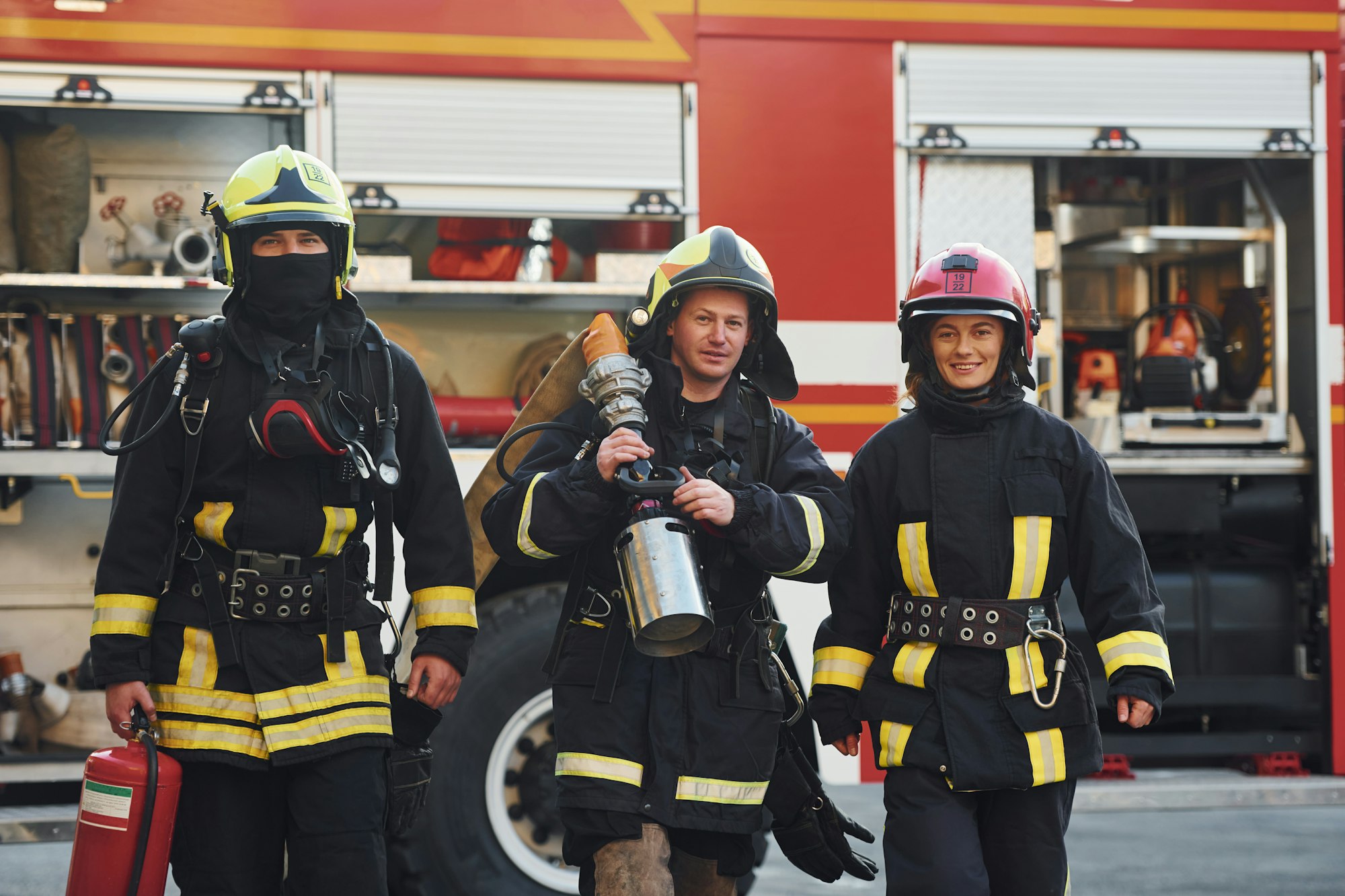 Group of firefighters in protective uniform that outdoors near truck