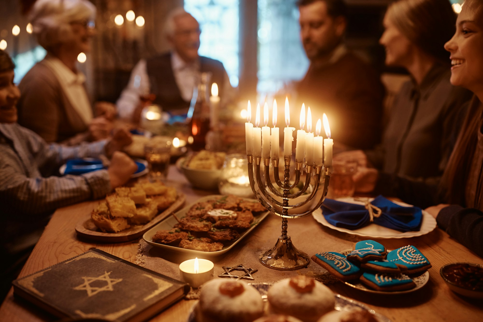 Lit candles in menorah during family meal at dining table on Hanukkah.