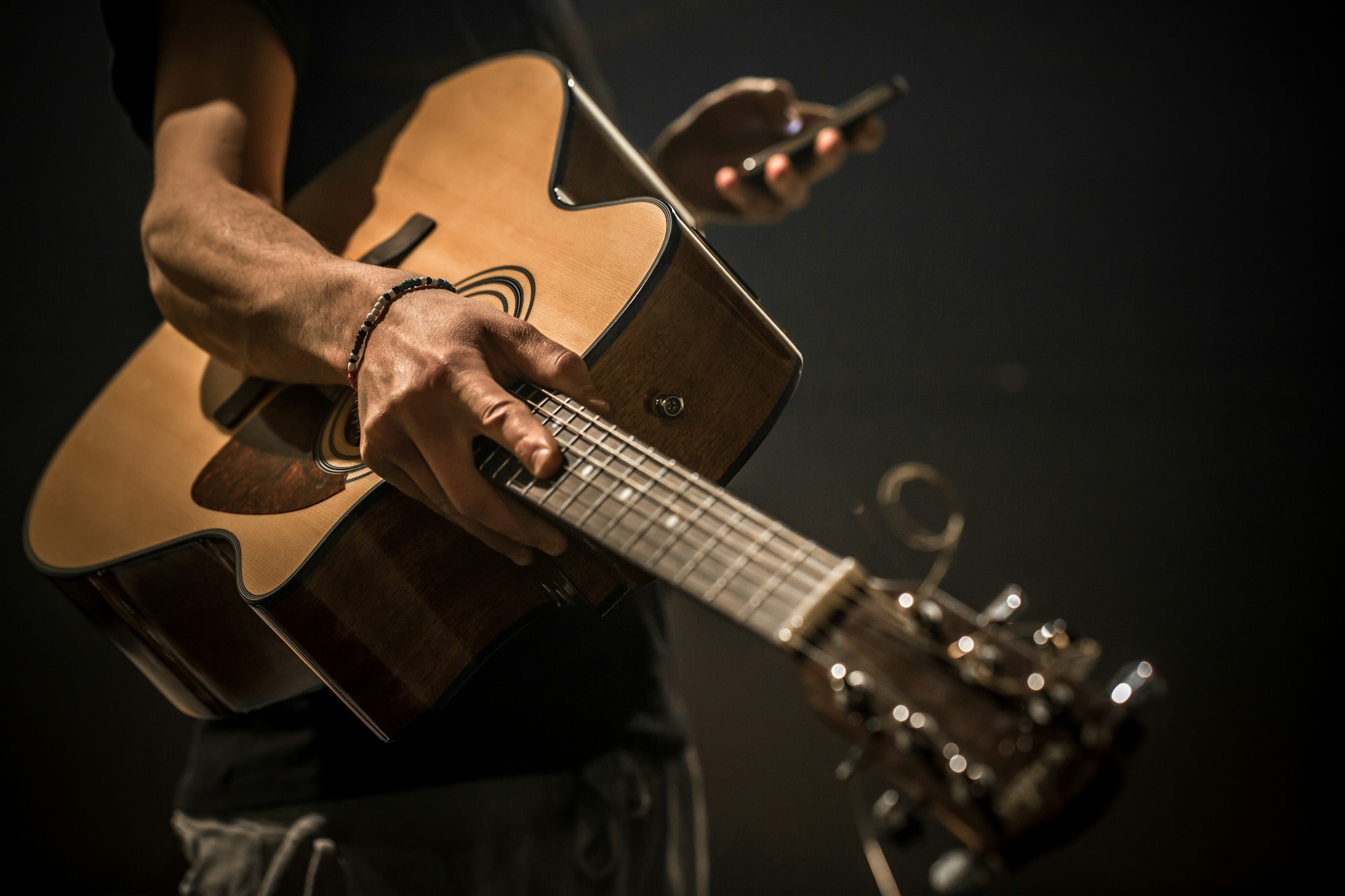 young man with acoustic guitar on black background