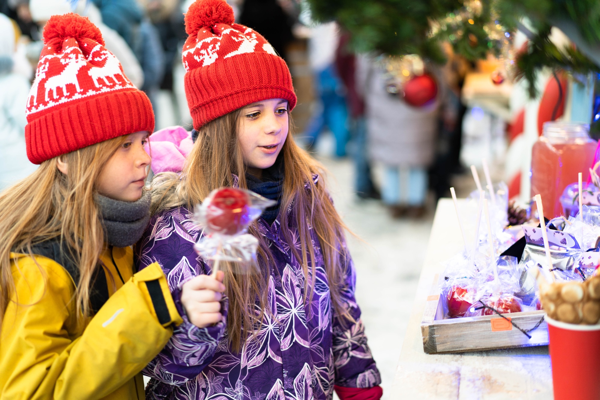 Two children in winter clothes choose homemade sweets at the Christmas market. Two children in winter clothes choose homemade sweets at the Christmas market.