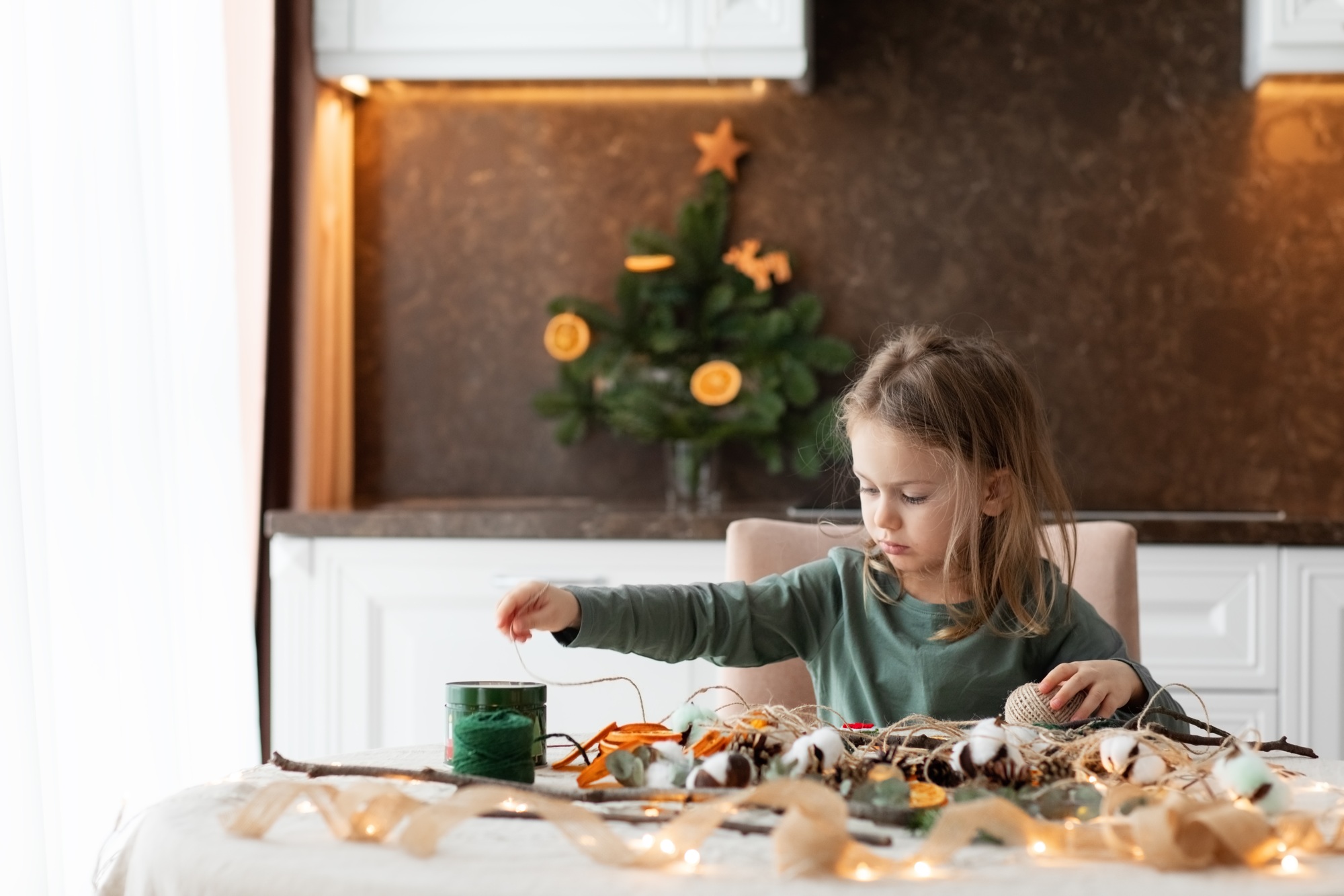 Winter holiday season. Happy child little girl making christmas decorations for crafting