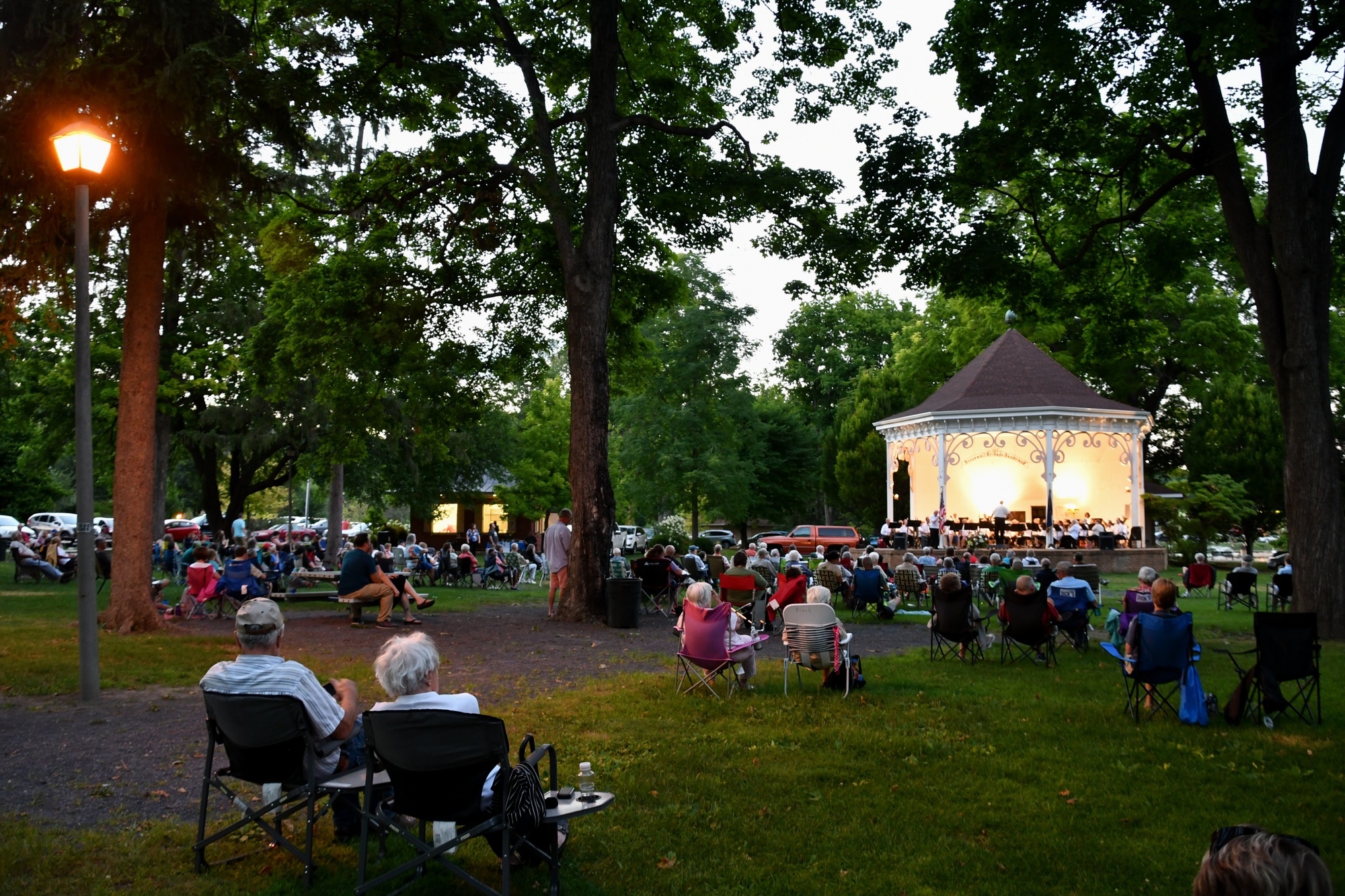 People in lawn chairs enjoying an outdoor concert at a park.