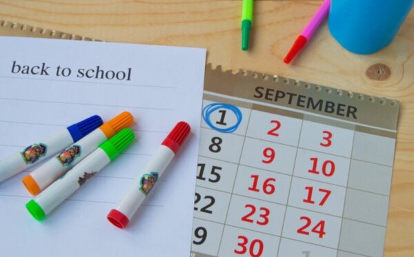 Back to school, calendar, colorful marker pens on wooden background