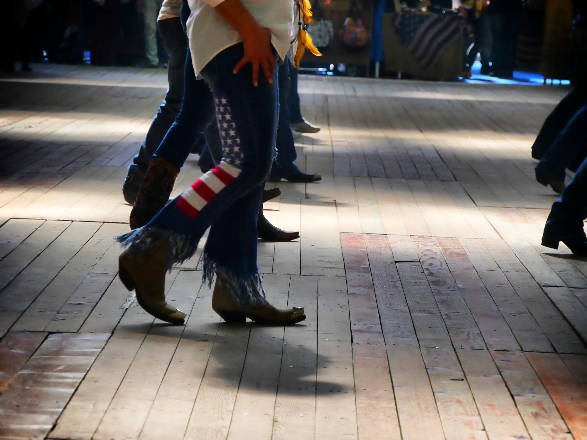 Western folk music dancer's legs in cowboy boots dancing on a wooden old floor